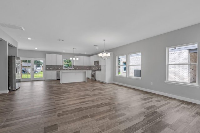 unfurnished living room with a chandelier and light hardwood / wood-style floors