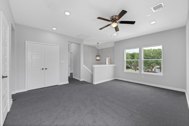 unfurnished living room featuring ceiling fan with notable chandelier and dark colored carpet