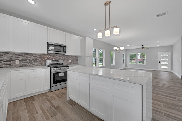 kitchen with pendant lighting, a center island, ceiling fan with notable chandelier, white cabinetry, and stainless steel appliances