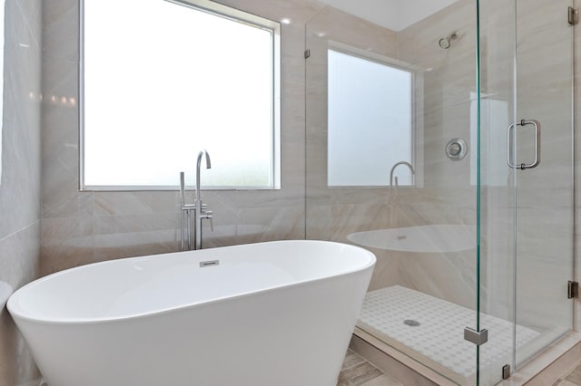 bathroom featuring tile walls and independent shower and bath