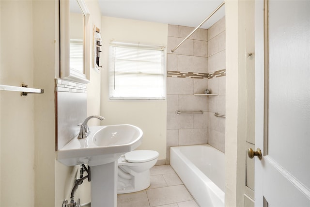 bathroom with tile patterned flooring, toilet, and tiled shower / bath