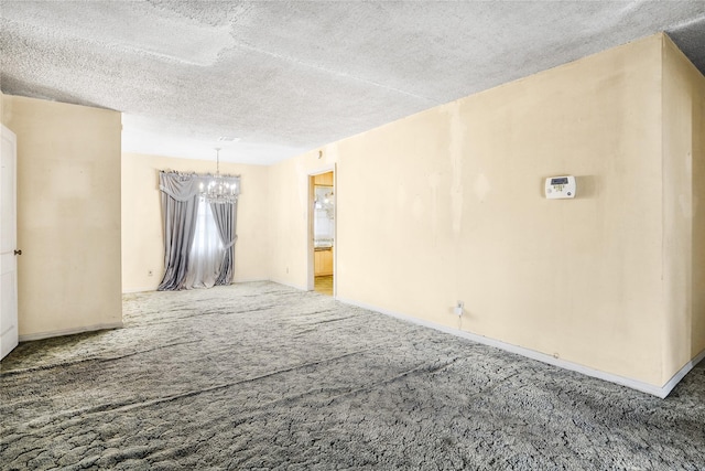 unfurnished room with a textured ceiling, carpet floors, and an inviting chandelier