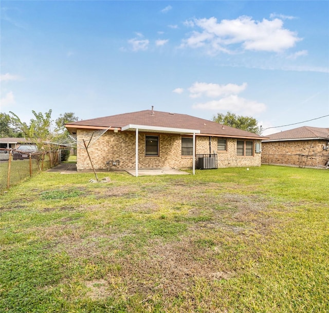 back of property with a lawn, central air condition unit, and a patio