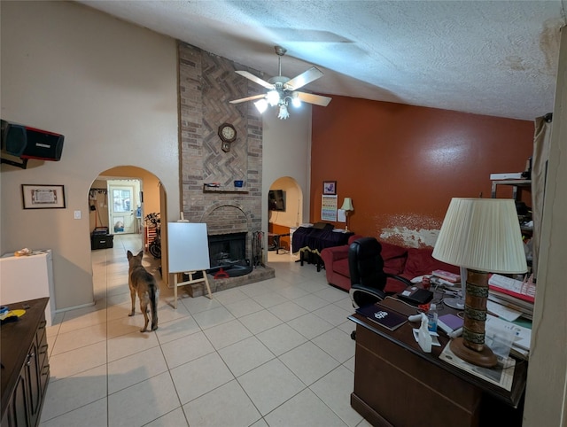 living room with high vaulted ceiling, ceiling fan, a textured ceiling, a fireplace, and light tile patterned flooring