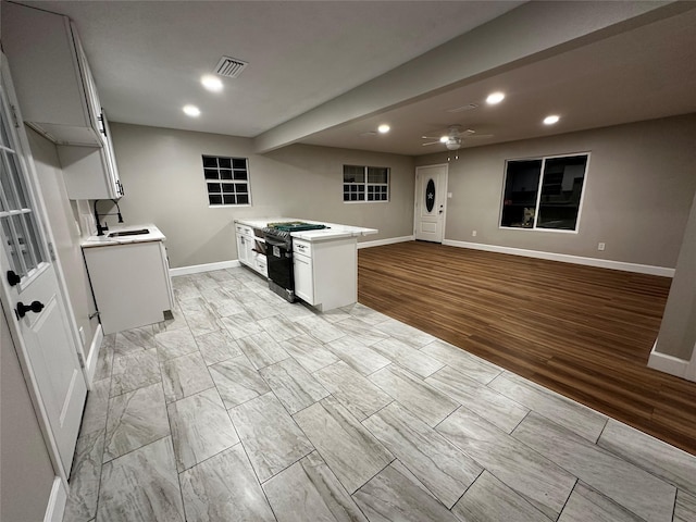 kitchen featuring white cabinets, sink, black range, and ceiling fan