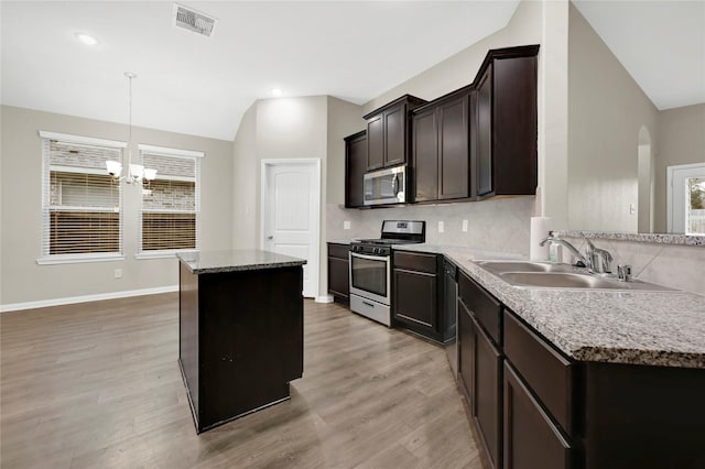 kitchen with a center island, lofted ceiling, sink, appliances with stainless steel finishes, and light hardwood / wood-style floors