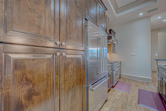 kitchen featuring crown molding, wall chimney exhaust hood, light hardwood / wood-style floors, and premium appliances