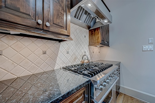 kitchen featuring backsplash, hardwood / wood-style flooring, wall chimney exhaust hood, high end stove, and dark brown cabinetry