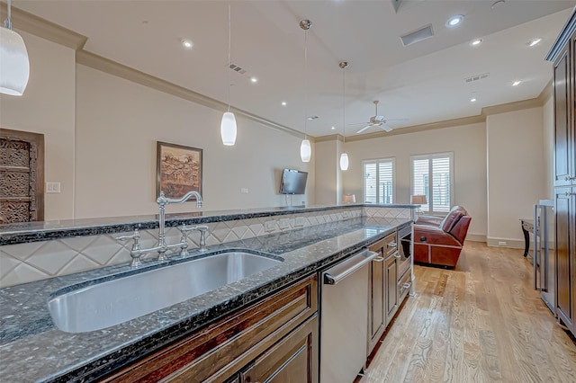 kitchen with dark stone countertops, pendant lighting, stainless steel appliances, and sink