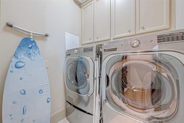 clothes washing area with cabinets and washing machine and clothes dryer