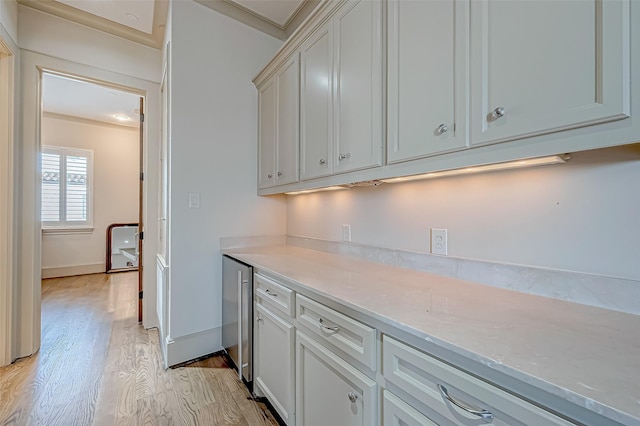 kitchen with light hardwood / wood-style floors, light stone counters, and crown molding