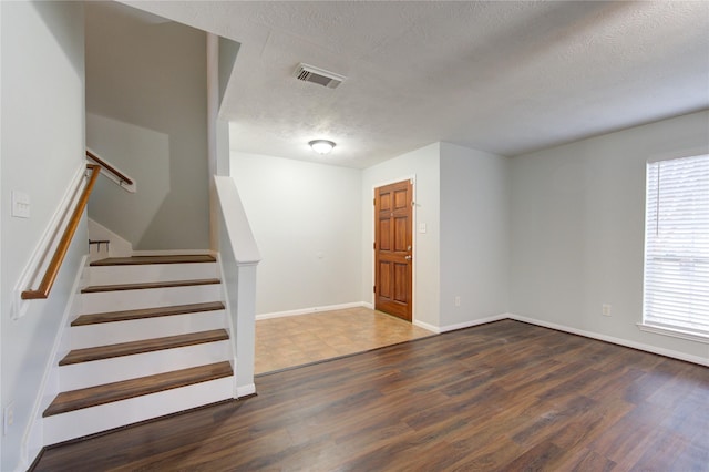 staircase featuring hardwood / wood-style floors and a textured ceiling