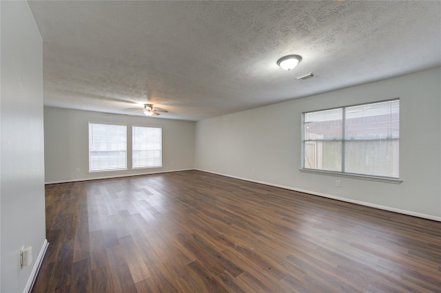 spare room featuring dark hardwood / wood-style floors, ceiling fan, and a textured ceiling