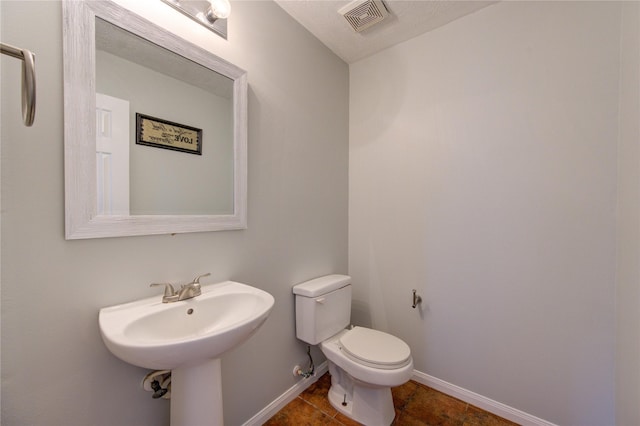 bathroom featuring tile patterned flooring, a textured ceiling, toilet, and sink