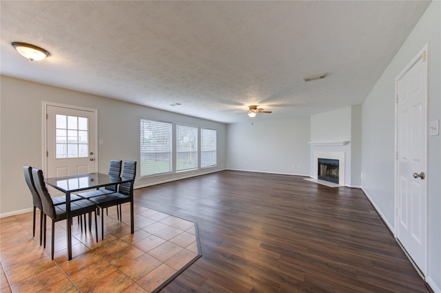 dining room with a textured ceiling, ceiling fan, and dark wood-type flooring