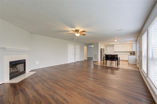 unfurnished living room with dark hardwood / wood-style floors, ceiling fan, and a wealth of natural light