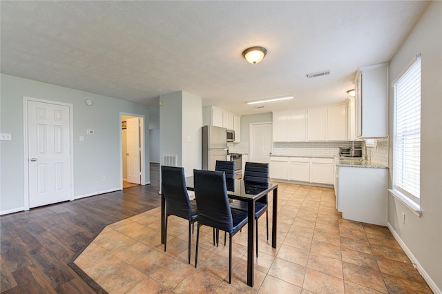 dining area with a textured ceiling and light wood-type flooring