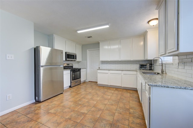 kitchen featuring decorative backsplash, appliances with stainless steel finishes, light stone countertops, sink, and white cabinets