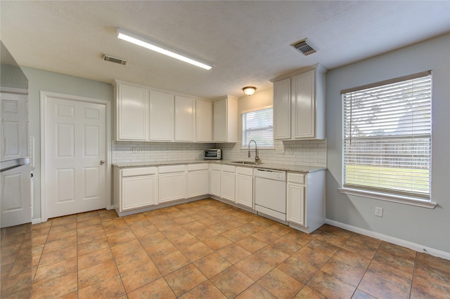 kitchen featuring decorative backsplash, light stone countertops, white cabinets, sink, and dishwasher