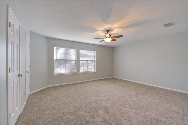 carpeted spare room featuring ceiling fan