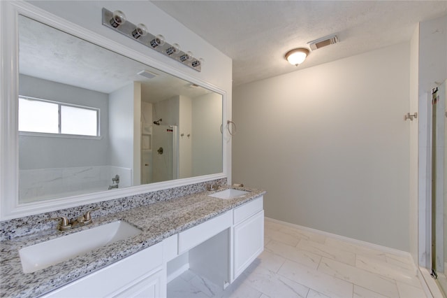 bathroom featuring vanity, a textured ceiling, and a shower with door