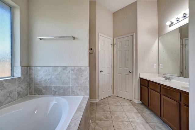 bathroom with tiled tub, tile patterned flooring, and vanity