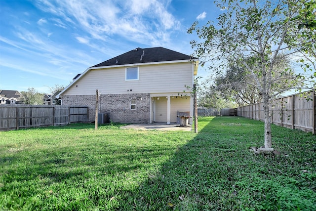 rear view of property featuring a lawn, central AC, and a patio area