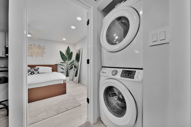 washroom with stacked washer and dryer and light hardwood / wood-style flooring