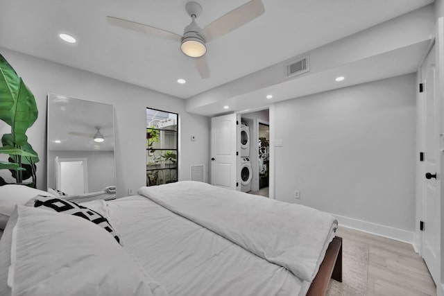 bedroom with stacked washer and dryer, ceiling fan, and light hardwood / wood-style floors