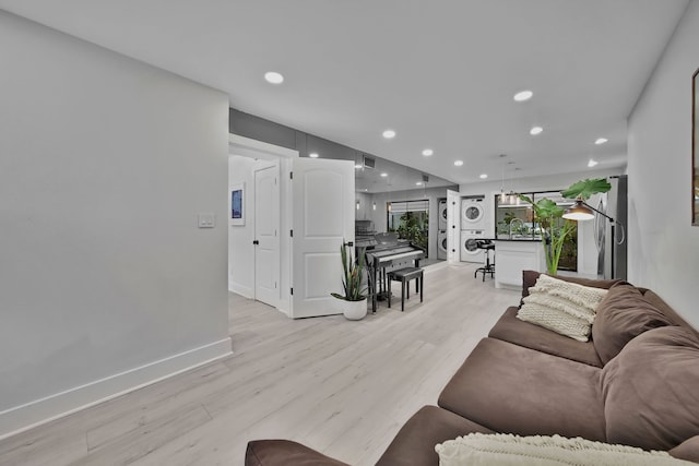 living room with light hardwood / wood-style flooring, stacked washer / dryer, and sink