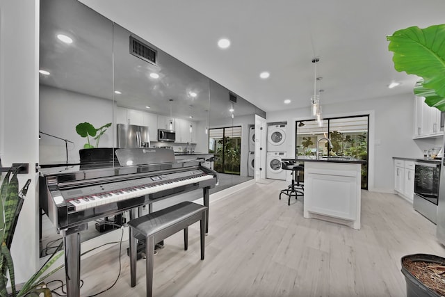 miscellaneous room with sink, stacked washer / dryer, and light hardwood / wood-style flooring