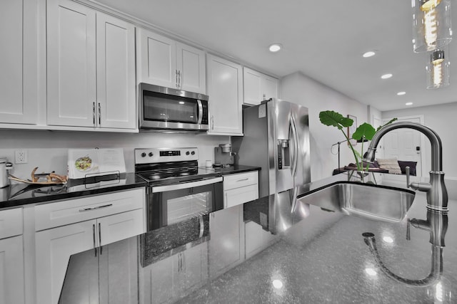 kitchen with white cabinetry, sink, hanging light fixtures, stainless steel appliances, and dark stone counters