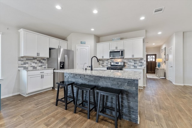 kitchen featuring appliances with stainless steel finishes, sink, white cabinets, and a center island with sink