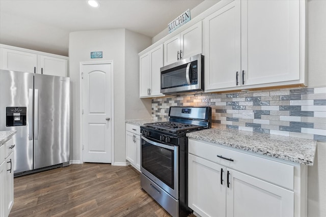 kitchen with light stone countertops, tasteful backsplash, appliances with stainless steel finishes, white cabinets, and dark hardwood / wood-style floors