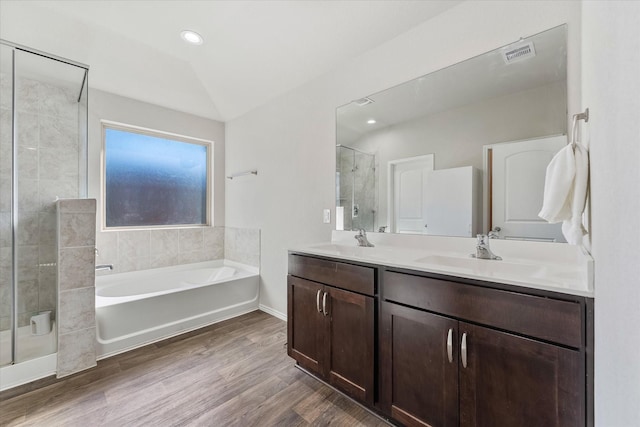 bathroom with hardwood / wood-style flooring, vanity, separate shower and tub, and lofted ceiling