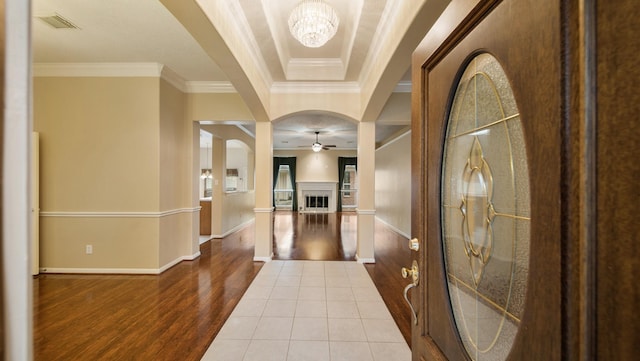 foyer entrance with crown molding, ceiling fan with notable chandelier, and hardwood / wood-style flooring