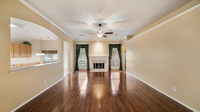 unfurnished living room with dark hardwood / wood-style floors, crown molding, a textured ceiling, and ceiling fan with notable chandelier