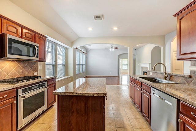 kitchen featuring sink, tasteful backsplash, light stone counters, light tile patterned floors, and appliances with stainless steel finishes