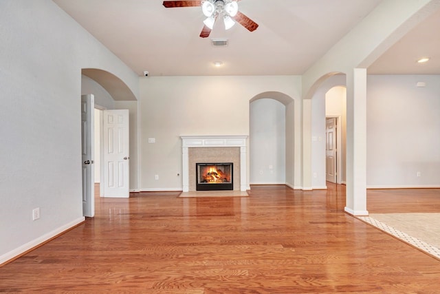 unfurnished living room featuring a premium fireplace, ceiling fan, and light hardwood / wood-style flooring