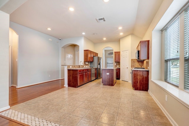 kitchen with light tile patterned flooring, stainless steel appliances, sink, and a kitchen island