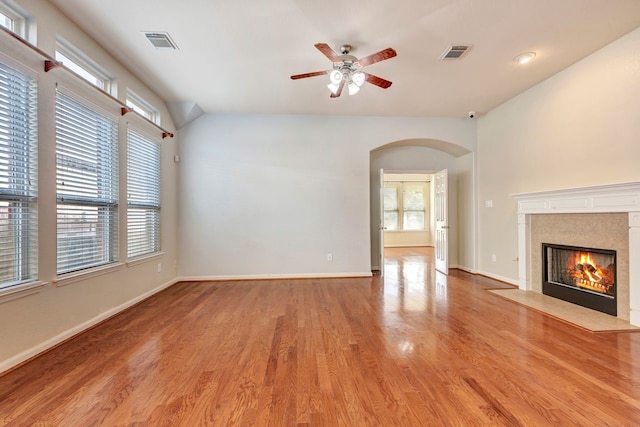 unfurnished living room featuring ceiling fan, a healthy amount of sunlight, a high end fireplace, and light hardwood / wood-style flooring