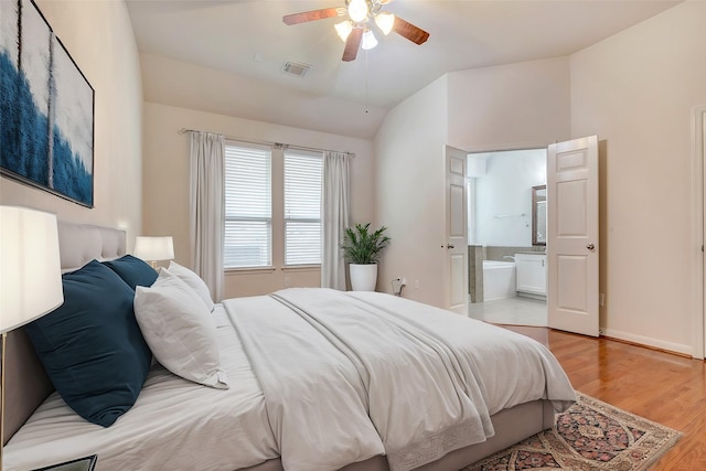 bedroom with vaulted ceiling, connected bathroom, ceiling fan, and light hardwood / wood-style flooring