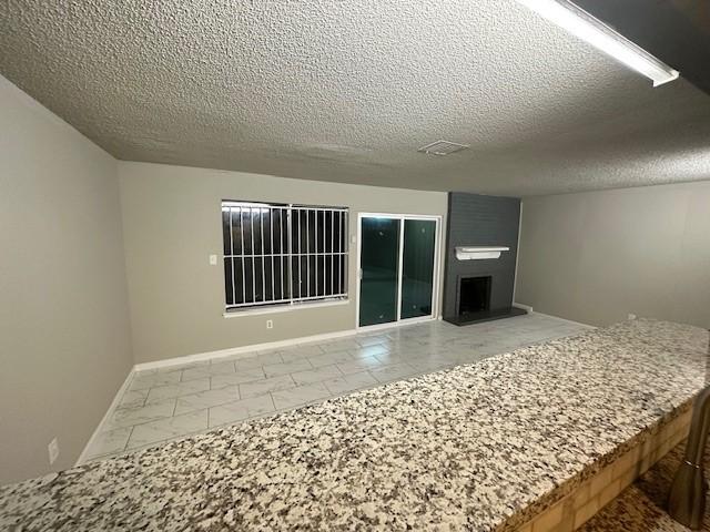 interior space with tile patterned floors, a large fireplace, and a textured ceiling