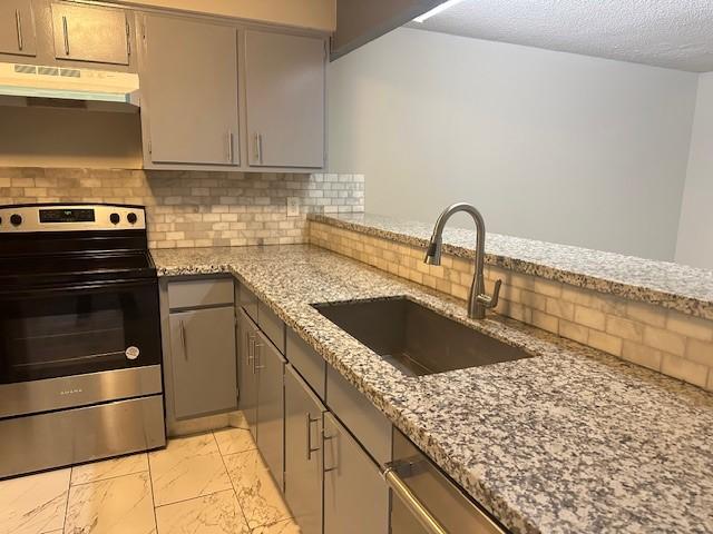 kitchen with gray cabinets, light stone counters, sink, and appliances with stainless steel finishes