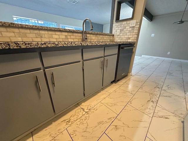 kitchen featuring dark stone counters, sink, stainless steel dishwasher, decorative backsplash, and gray cabinets