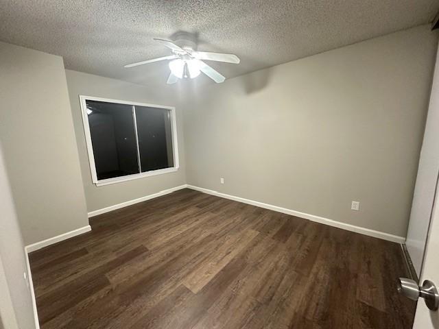 empty room with ceiling fan, dark hardwood / wood-style flooring, and a textured ceiling