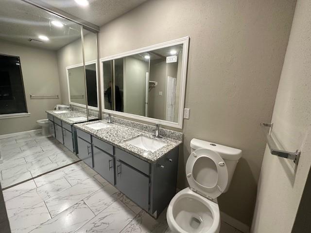 bathroom featuring vanity, a textured ceiling, and toilet