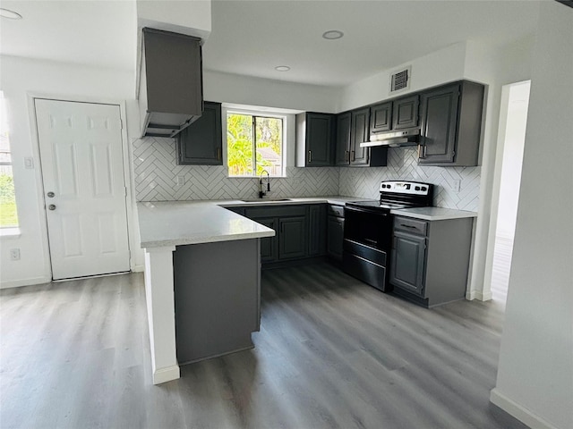 kitchen with electric range, sink, kitchen peninsula, gray cabinets, and hardwood / wood-style flooring