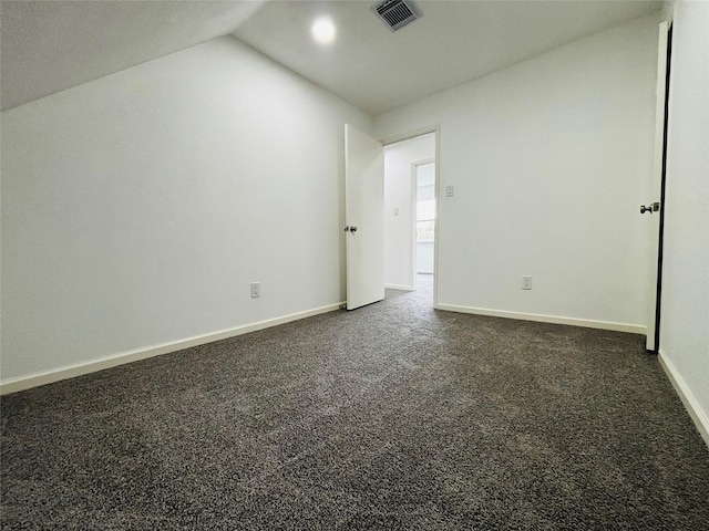 empty room with dark carpet and lofted ceiling