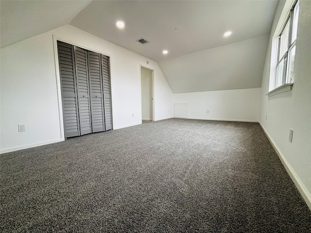 additional living space featuring dark colored carpet and lofted ceiling